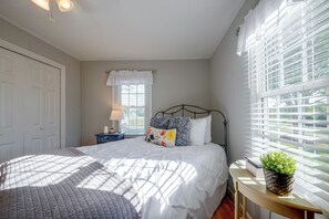 A bedroom with a bed, a bedside table with a lamp, a window with blinds, and a door. - Peaceful Elkin Vacation Rental ~ 17 Mi to Mt Airy! (Elkin)