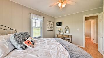 A bedroom with a bed, a ceiling fan, a dresser, and a television.