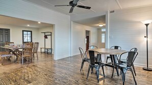 A spacious dining area with a wooden table and chairs, a ceiling fan, and a modern light fixture. - Fire Pit, Pickleball, Pool! Schulenburg Farmhouse (Schulenburg)