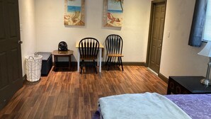 Een slaapkamer met een bed, twee stoelen, een tafeltje en twee schilderijen aan de muur.