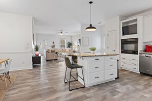 Una cocina moderna con armarios blancos, encimera de granito y horno empotrado.