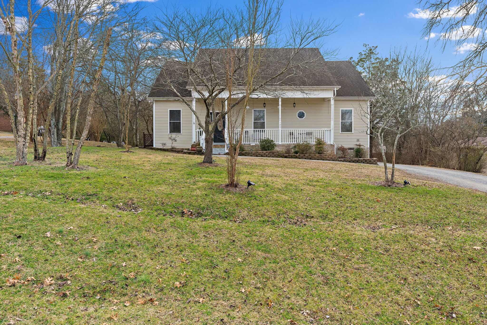 A two-story house with a front porch, a small front yard, and a driveway.