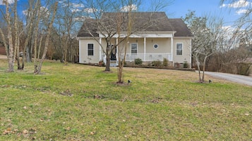 A two-story house with a front porch, a small front yard, and a driveway.
