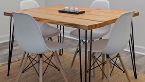 Un comedor con una mesa de madera, sillas blancas, una lámpara moderna, una obra de arte abstracto enmarcada y una estantería con plantas.
