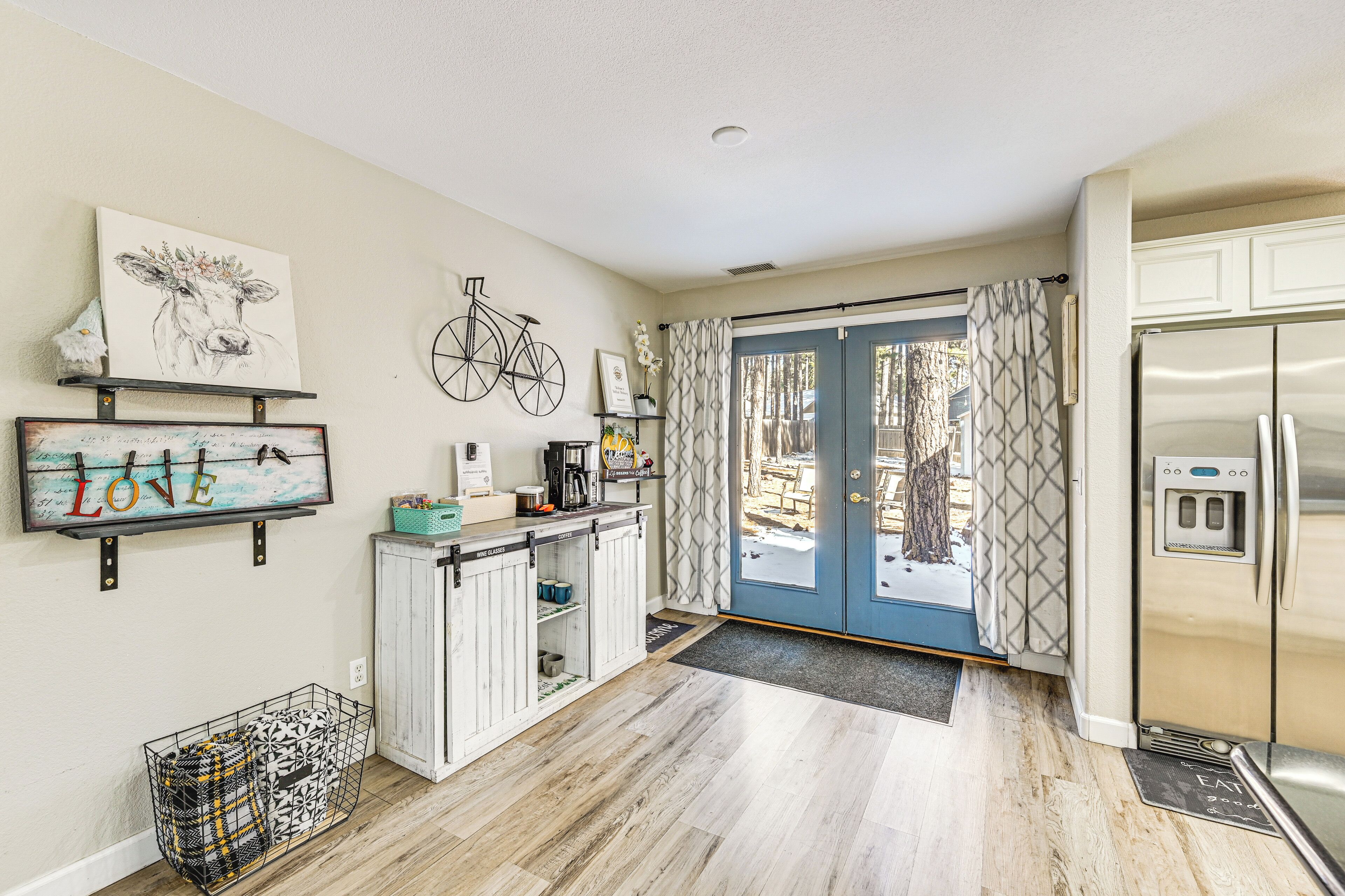 A kitchen with a refrigerator, a coffee maker, and a shelf with decorative items.