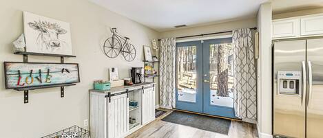 A kitchen with a refrigerator, a coffee maker, and a shelf with decorative items.