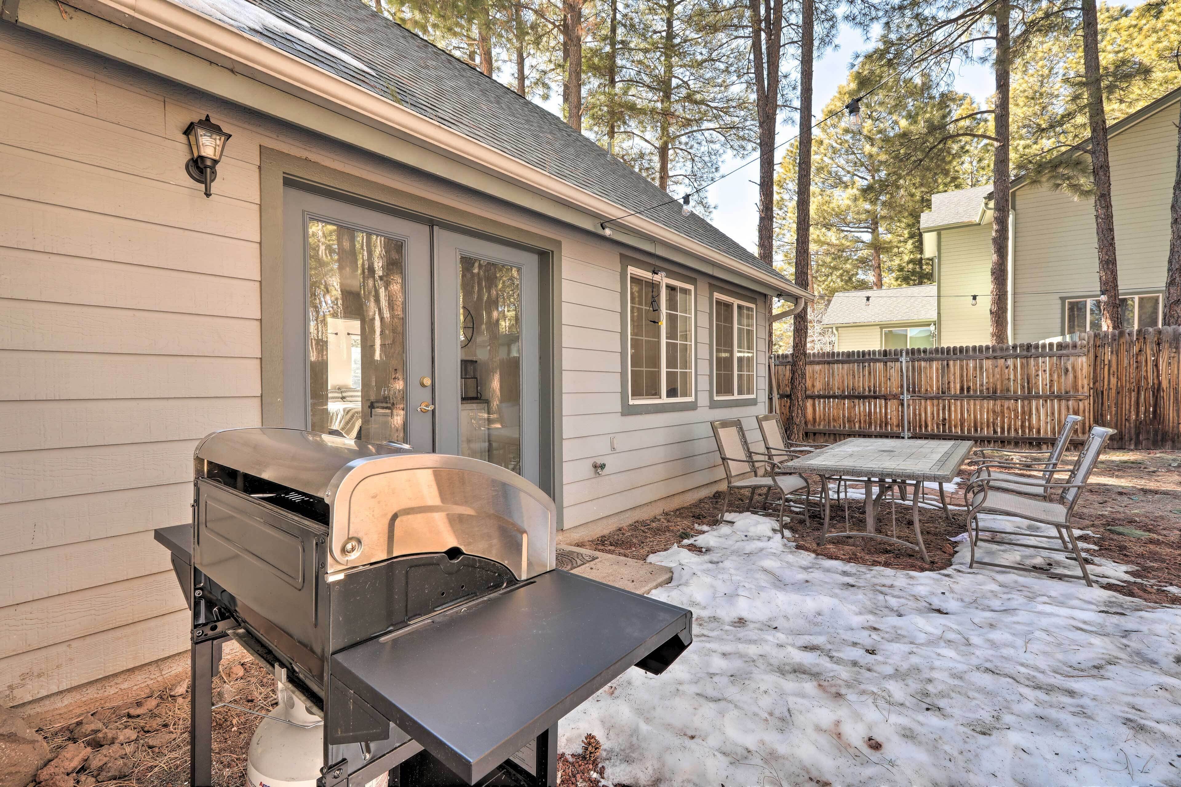 A backyard with a barbecue grill, a table, and chairs.