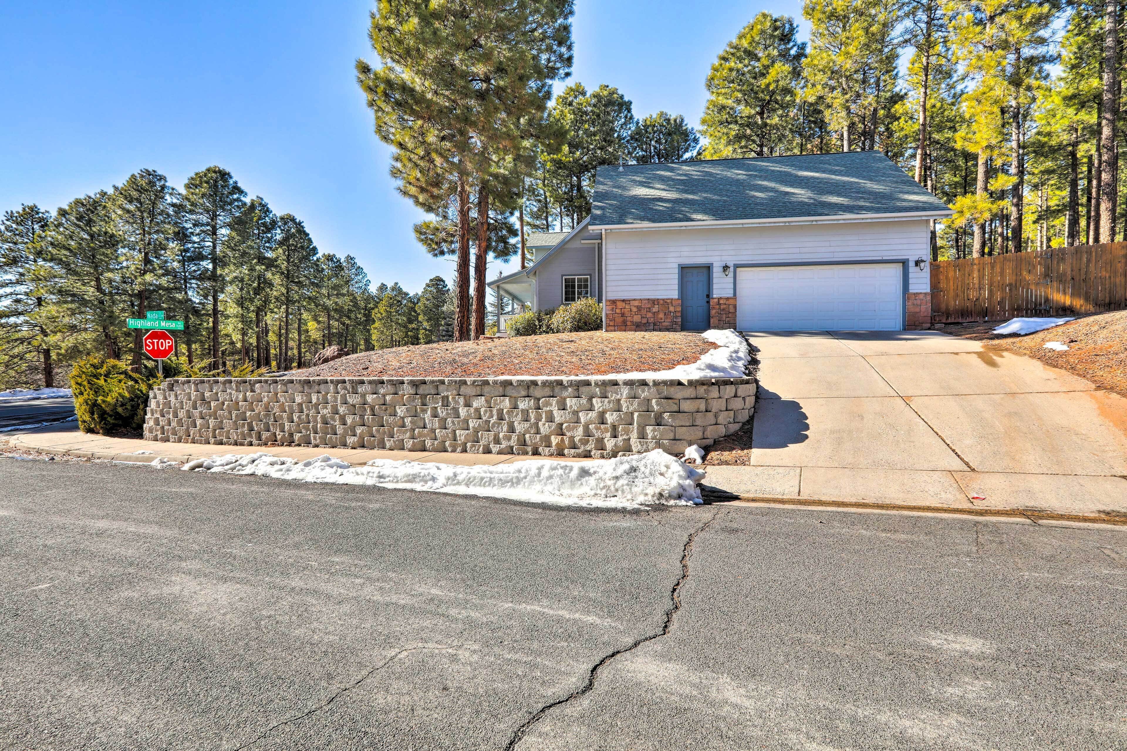 A two-story house with a garage, surrounded by a stone retaining wall and a wooden fence.