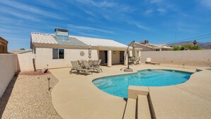 A house with a swimming pool, outdoor furniture, and a clear blue sky.
