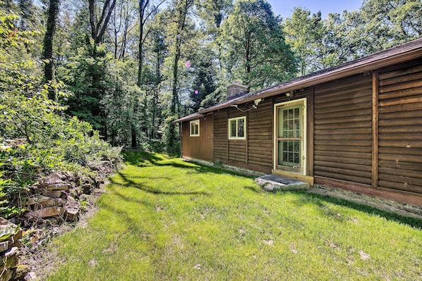 A wooden cabin with a small front porch and a stone wall on the left. - Hike, Hunt & Unwind: Cozy Cabin Near Hersheypark (Jonestown)