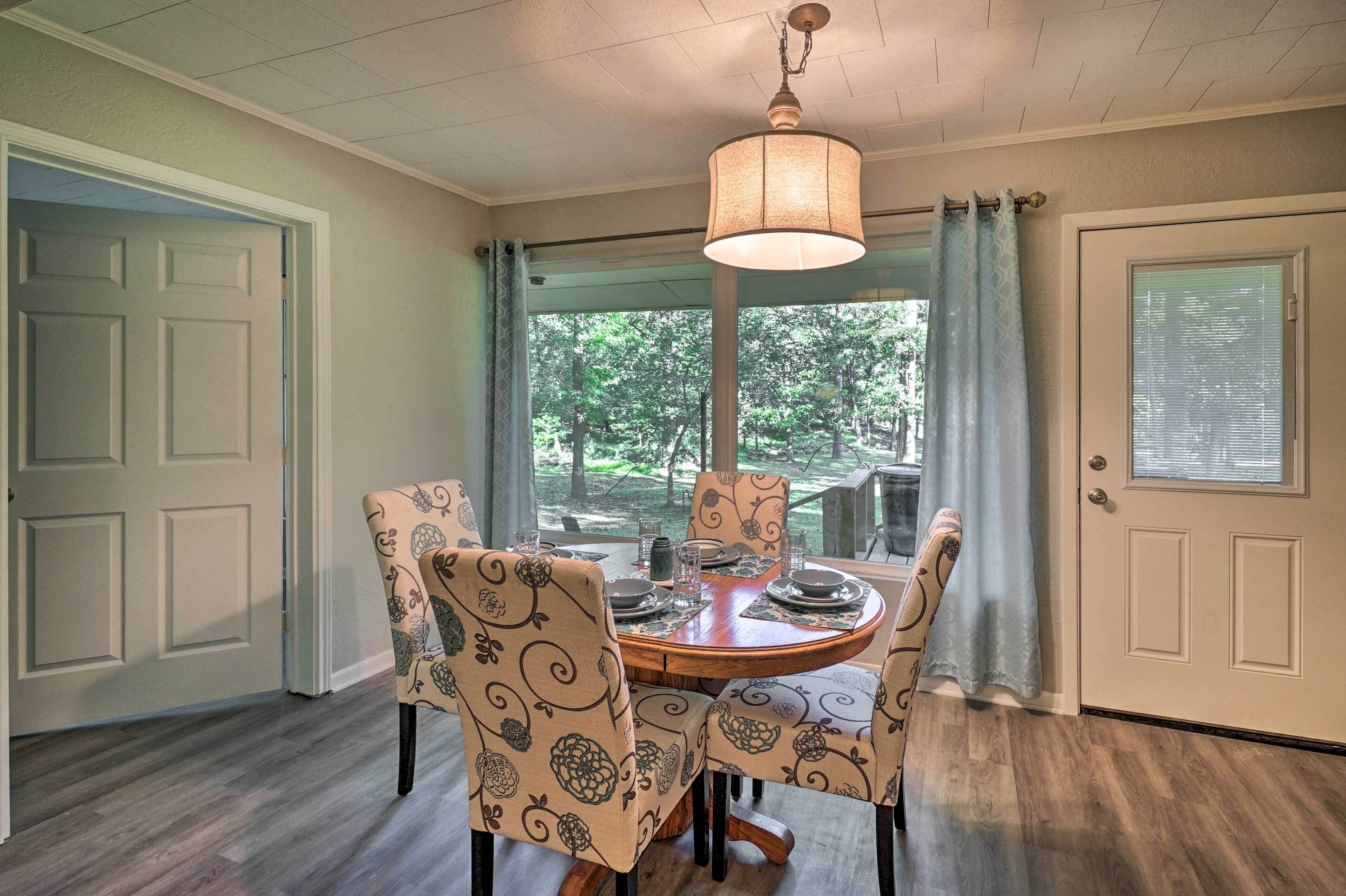 A dining area with a round table, patterned chairs, and a hanging light fixture.