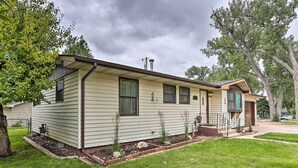 A single-story mobile home with a front porch, a chimney, and a small front yard with a lawn and a few plants. - Rapid City Home - Walk to Canyon Lake Park (Rapid City)