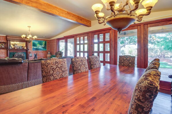 A dining area with a wooden table, patterned chairs, a fireplace, and a chandelier.