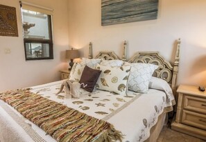 A bedroom with a bed, nightstands, a lamp, and a window.
