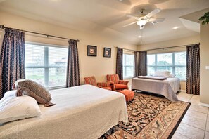 Two comfortable beds, a ceiling fan, and a large window with curtains make this room a serene retreat.