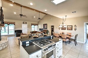 A spacious kitchen with a central island, a dining area with a chandelier, and a living room with a fireplace. - Pet-friendly Flatonia House w/ Patio & Gazebo! (Flatonia)