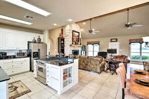 A spacious kitchen with white cabinets, a central island, and a stone fireplace. - Pet-friendly Flatonia House w/ Patio & Gazebo! (Flatonia)