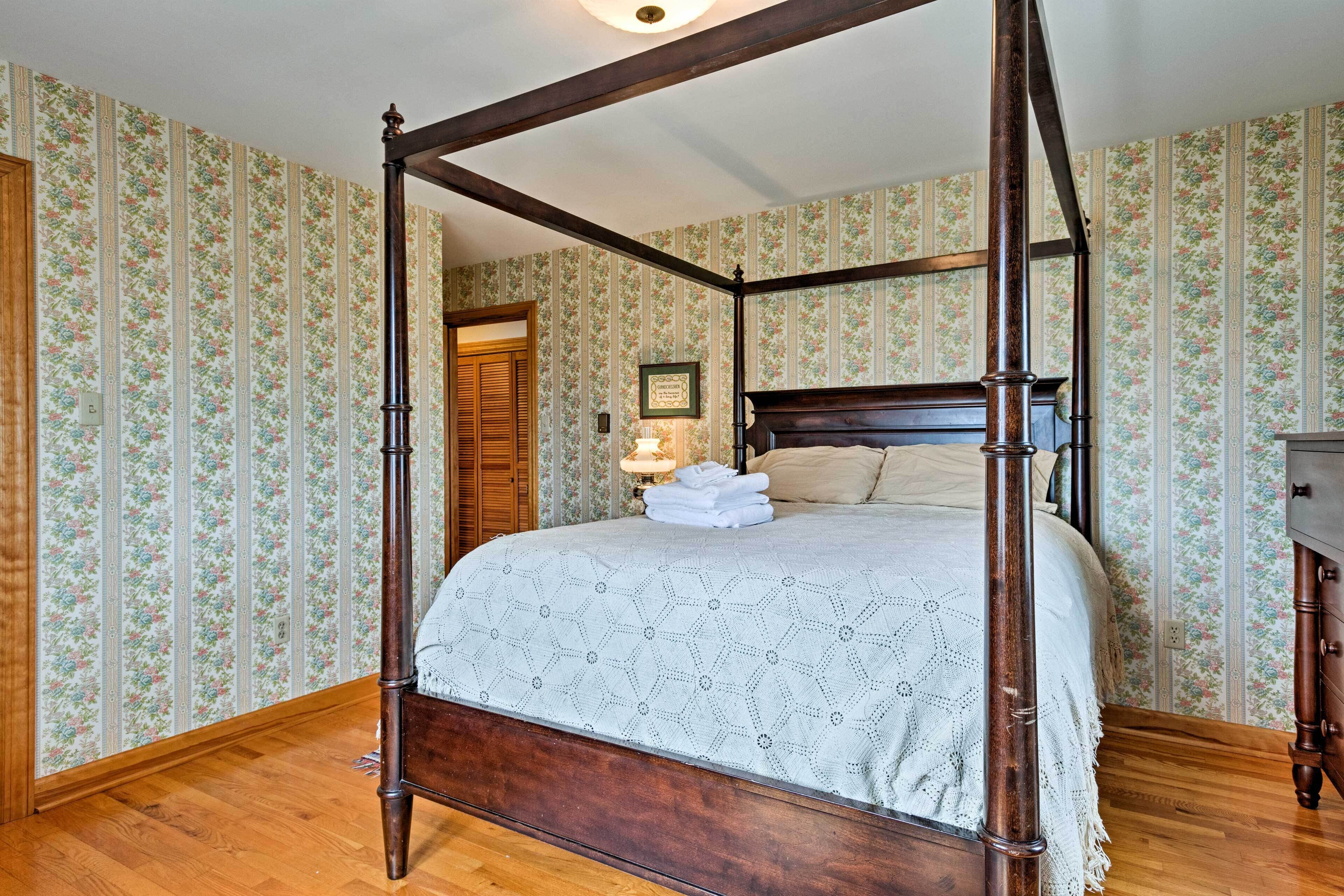 A four-poster bed with a wooden frame and a geometric patterned bedspread.