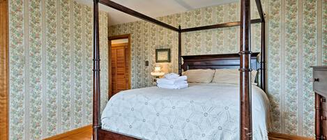 A four-poster bed with a wooden frame and a geometric patterned bedspread.