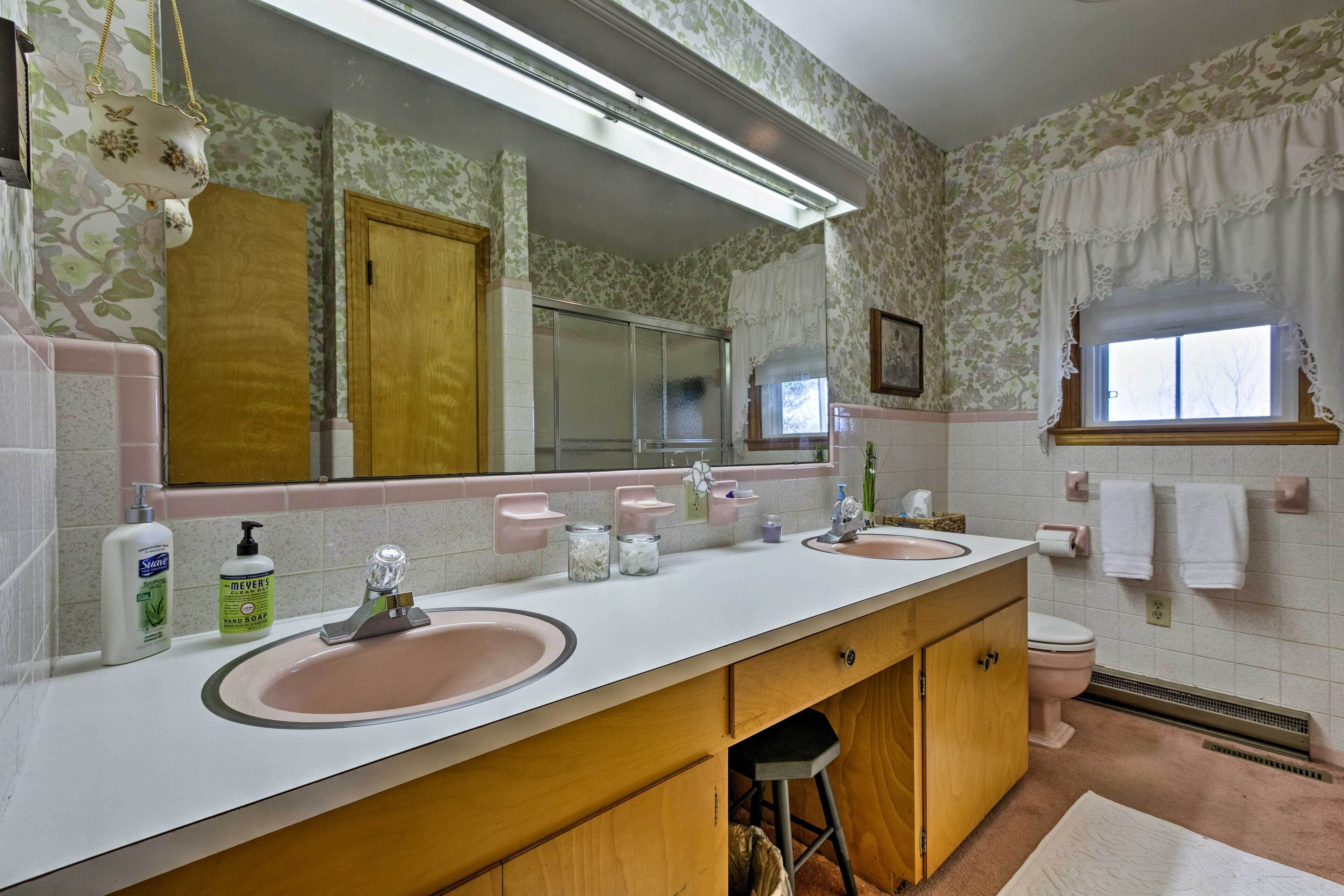 Un baño con dos lavamanos, un espejo grande y un inodoro.