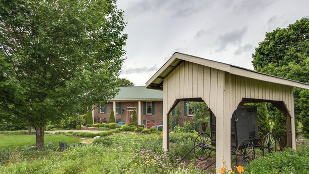 A house with a garden, a covered porch, and a green roof.