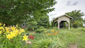 A garden with a gazebo, a brick building, and various flowers.