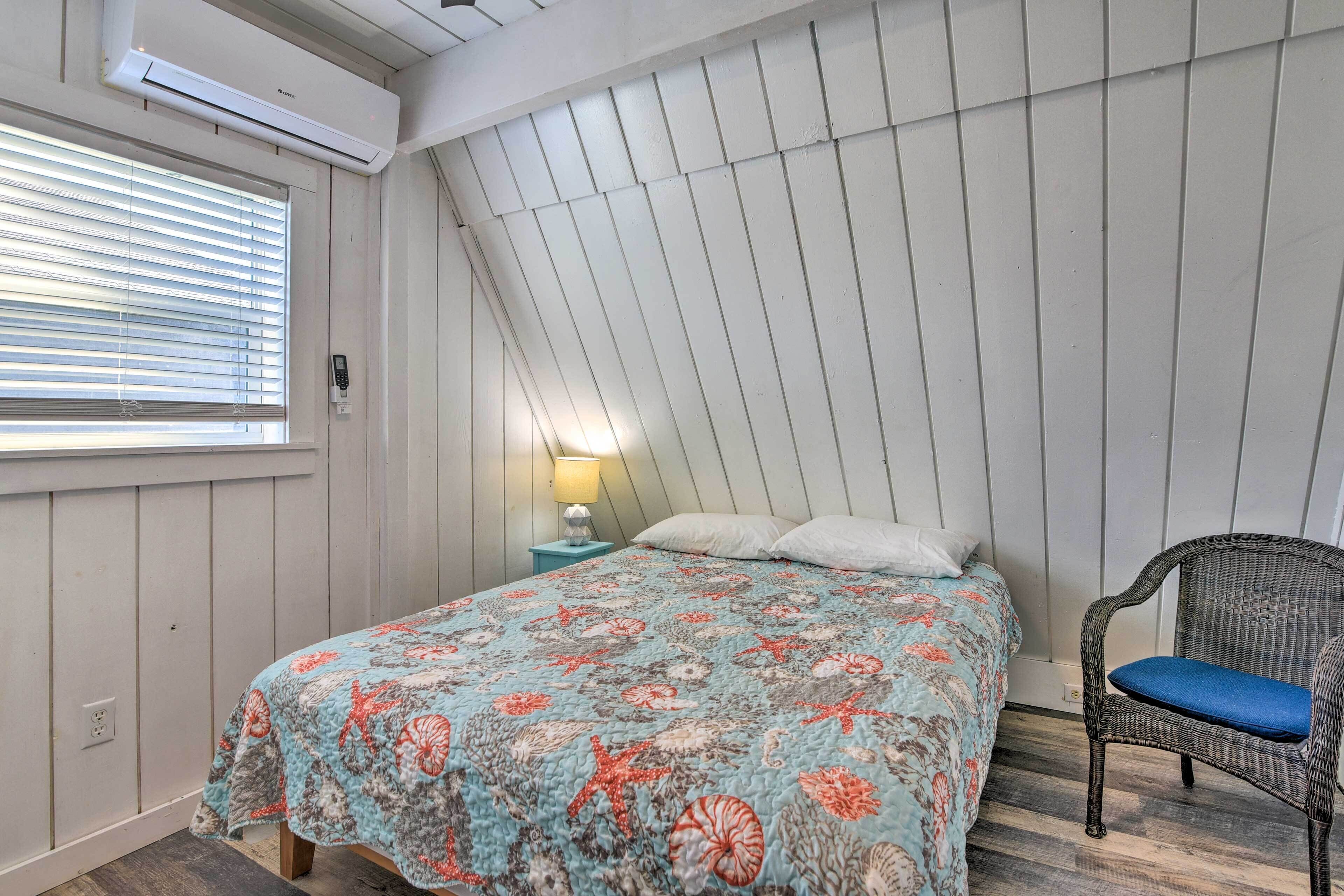 A bedroom with a bed, a chair, a nightstand, and a window with blinds.