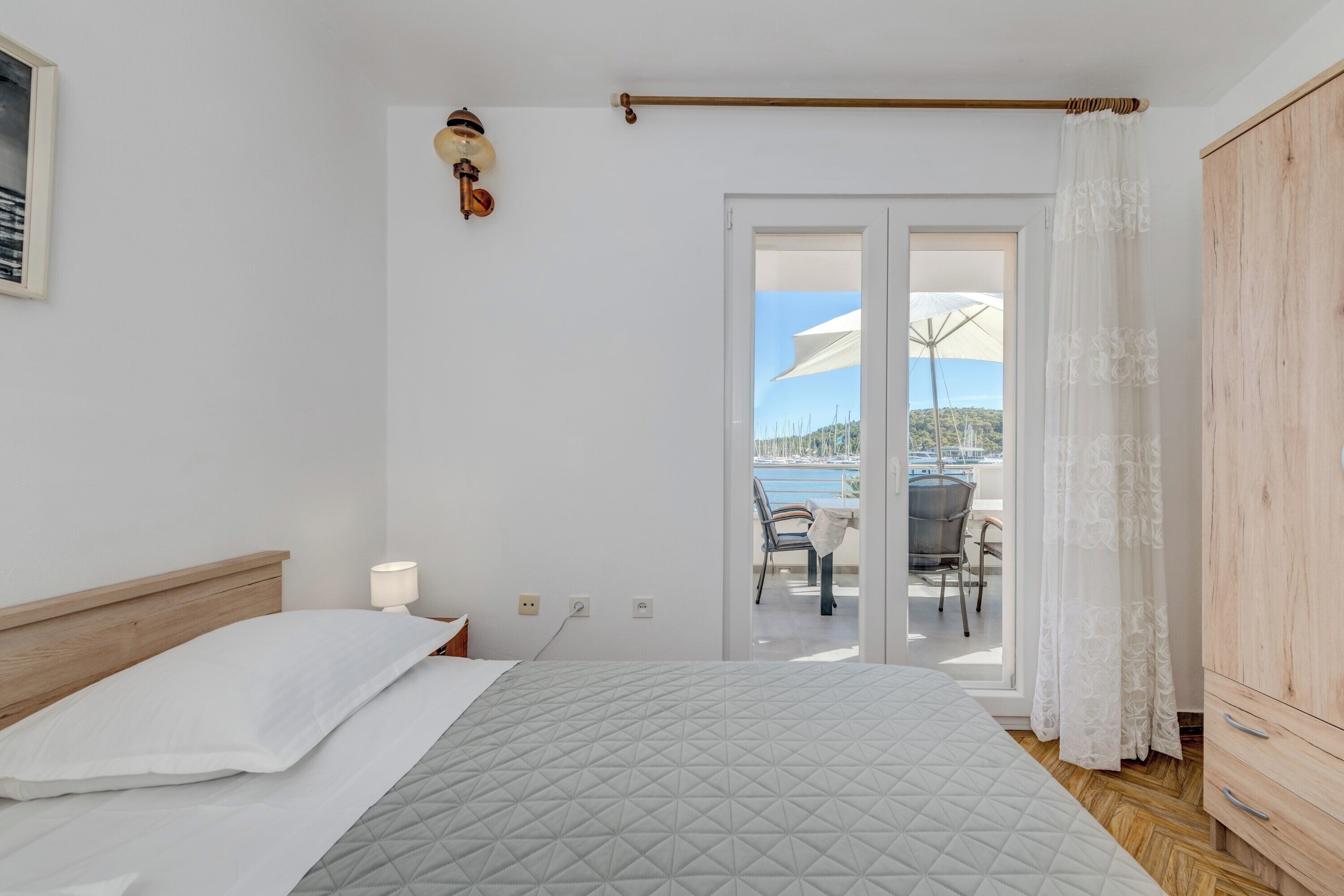 Un dormitorio con una cama, un armario de madera y vistas a una terraza exterior con mesa y sillas.
