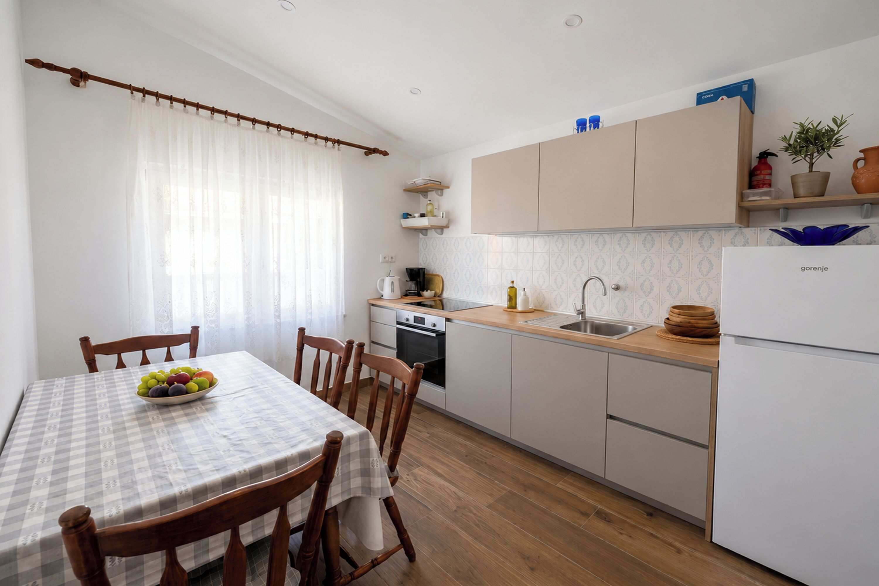 A kitchen with a dining table, chairs, a refrigerator, and a sink.