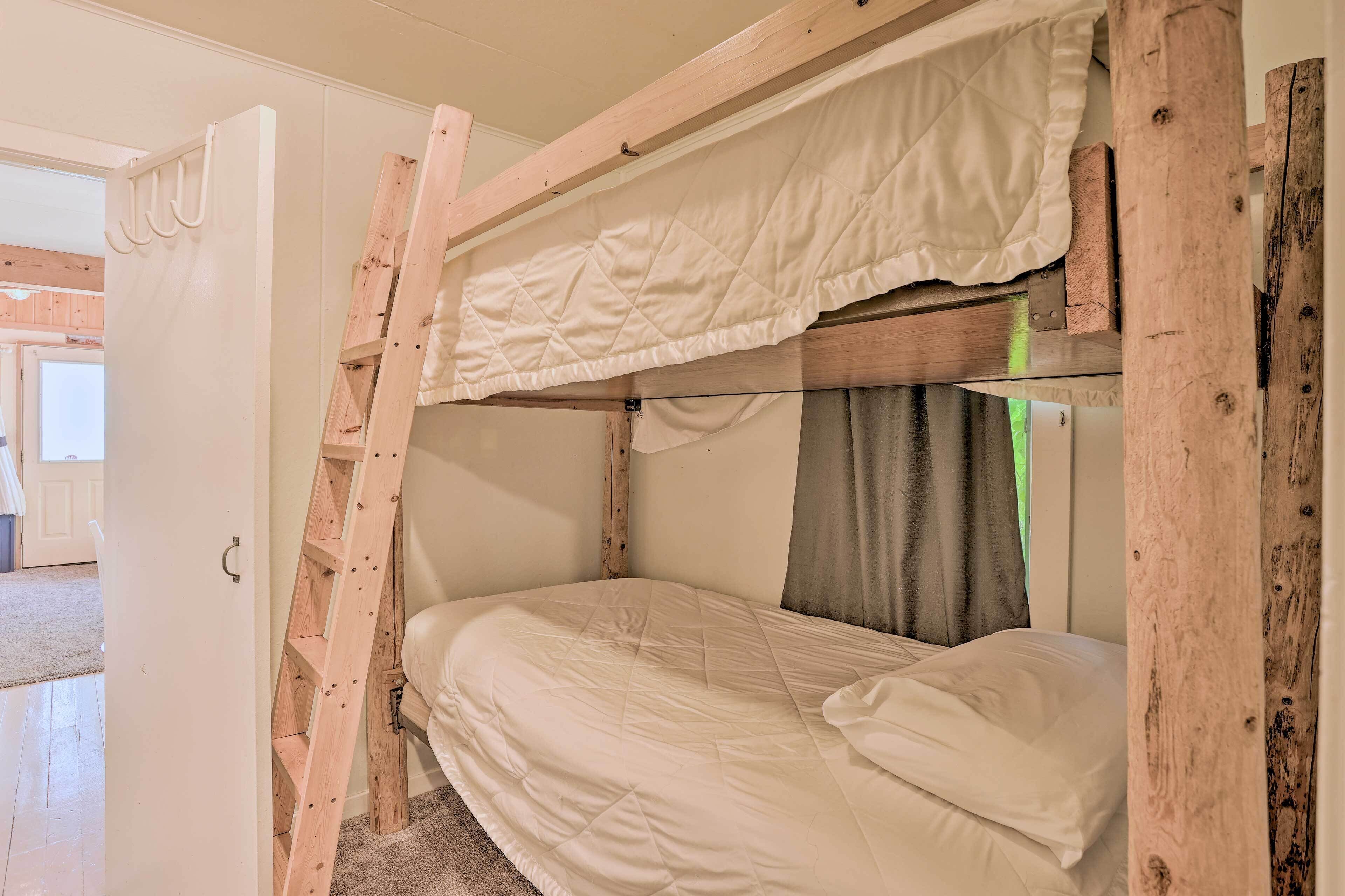 Een stapelbed met een gewatteerde hoofdrail en een houten trap.