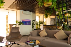 Un interior moderno con sofá, sillón y una mesa de vidrio con un cuaderno y bolígrafo.