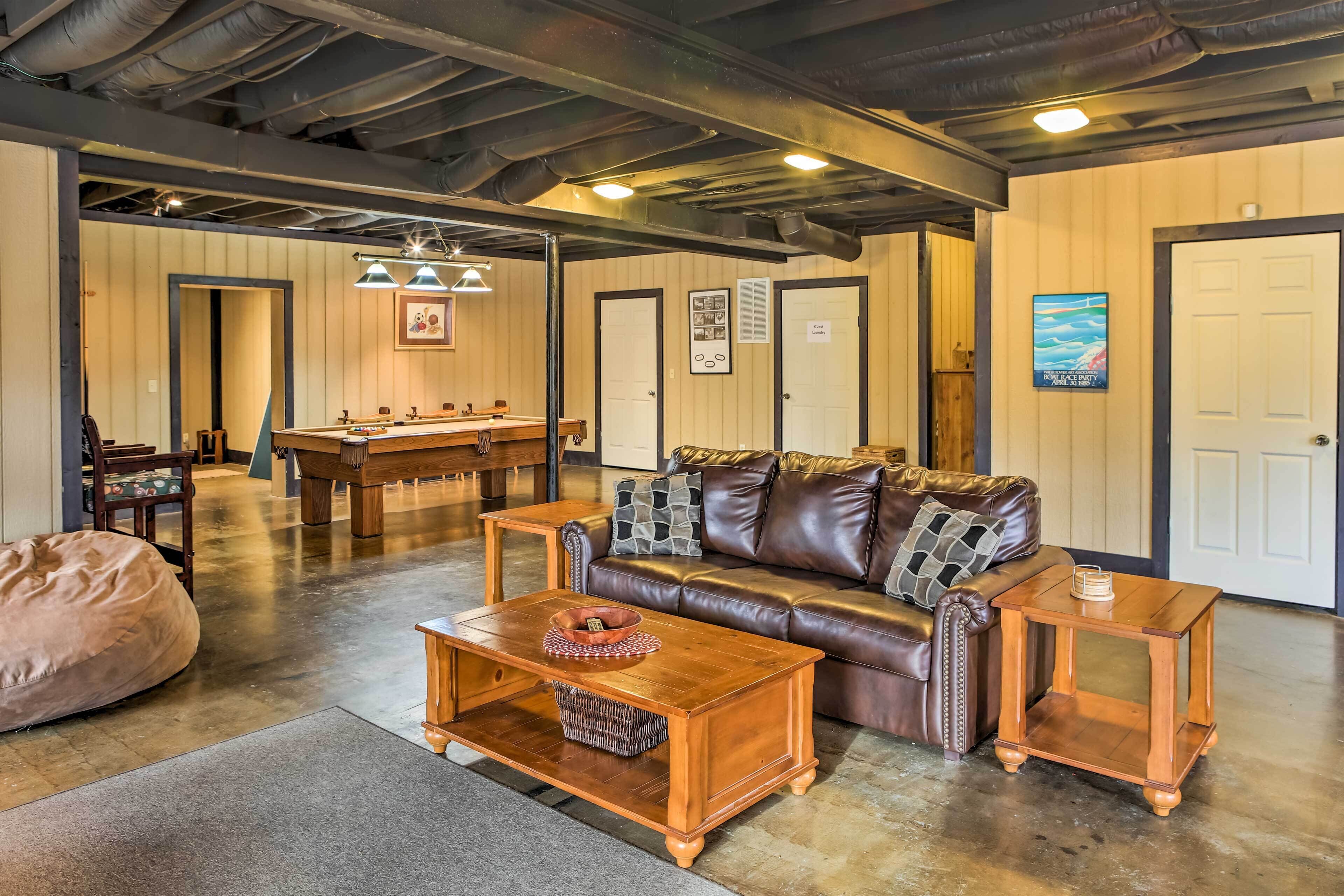 A cozy living room with a leather couch, wooden coffee table, and a pool table.