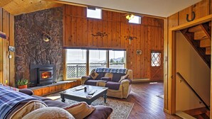 Ein gemütliches Wohnzimmer mit Kamin, Holzwänden, einer Couch und einer Treppe.