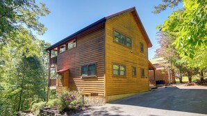 A two-story log cabin with a porch and a covered front entrance.
