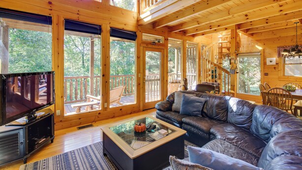 A spacious living room with a large leather sofa, a coffee table, and a flat-screen TV.