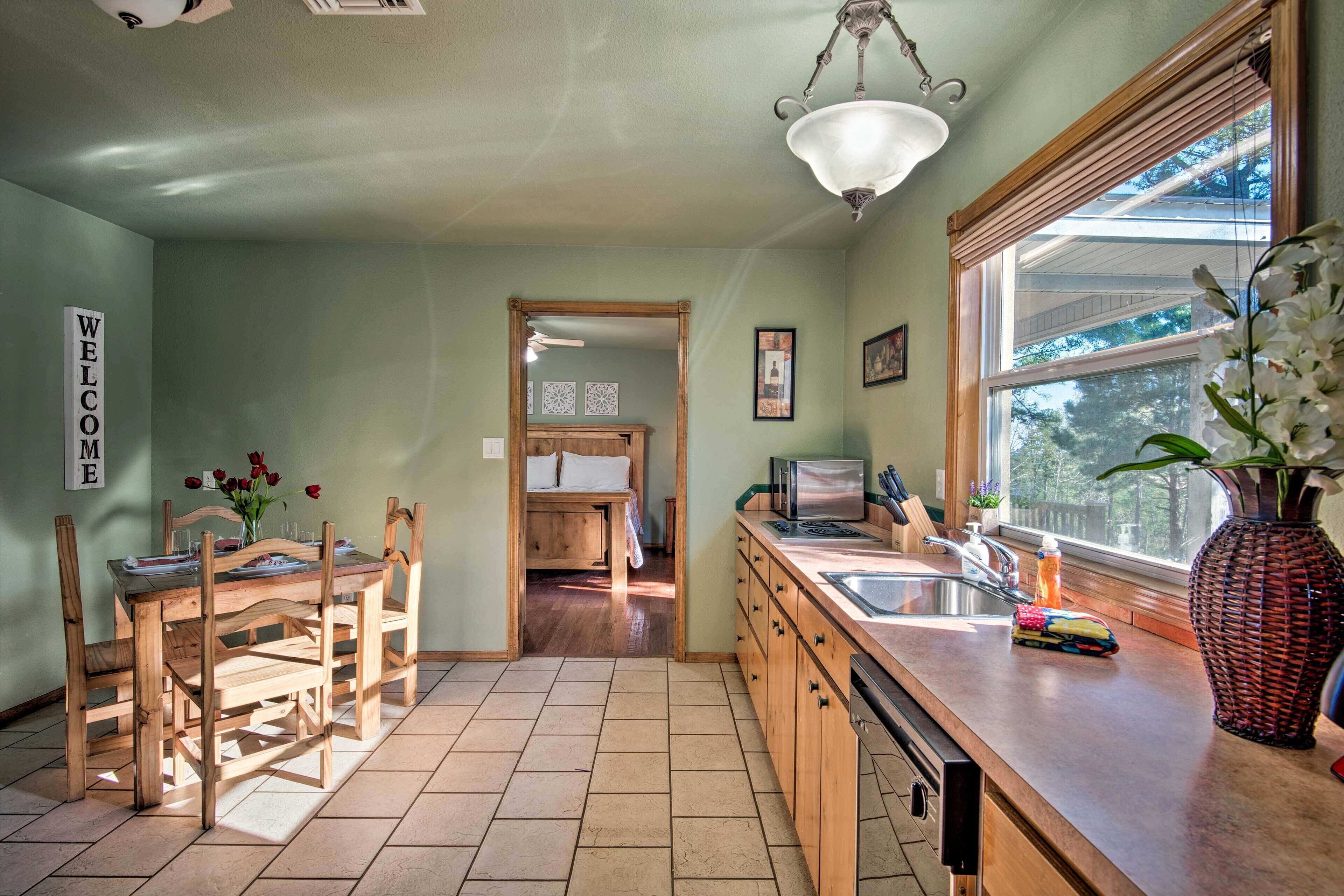 A kitchen with wooden cabinets, a sink, and a dining area with a table and chairs.