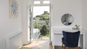 A modern room with a view of a castle, a desk with a mirror, and a chair. - Golygfa'r Gastell / Castle View (Criccieth)