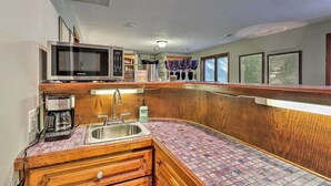 A compact kitchen with a microwave, coffee maker, and a sink.