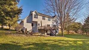A two-story house with a front porch, a stone pathway, and a large tree in the yard.