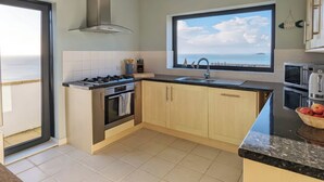 Eine moderne Küche mit Gasherd, Backofen und einem großen Fenster mit Meerblick.