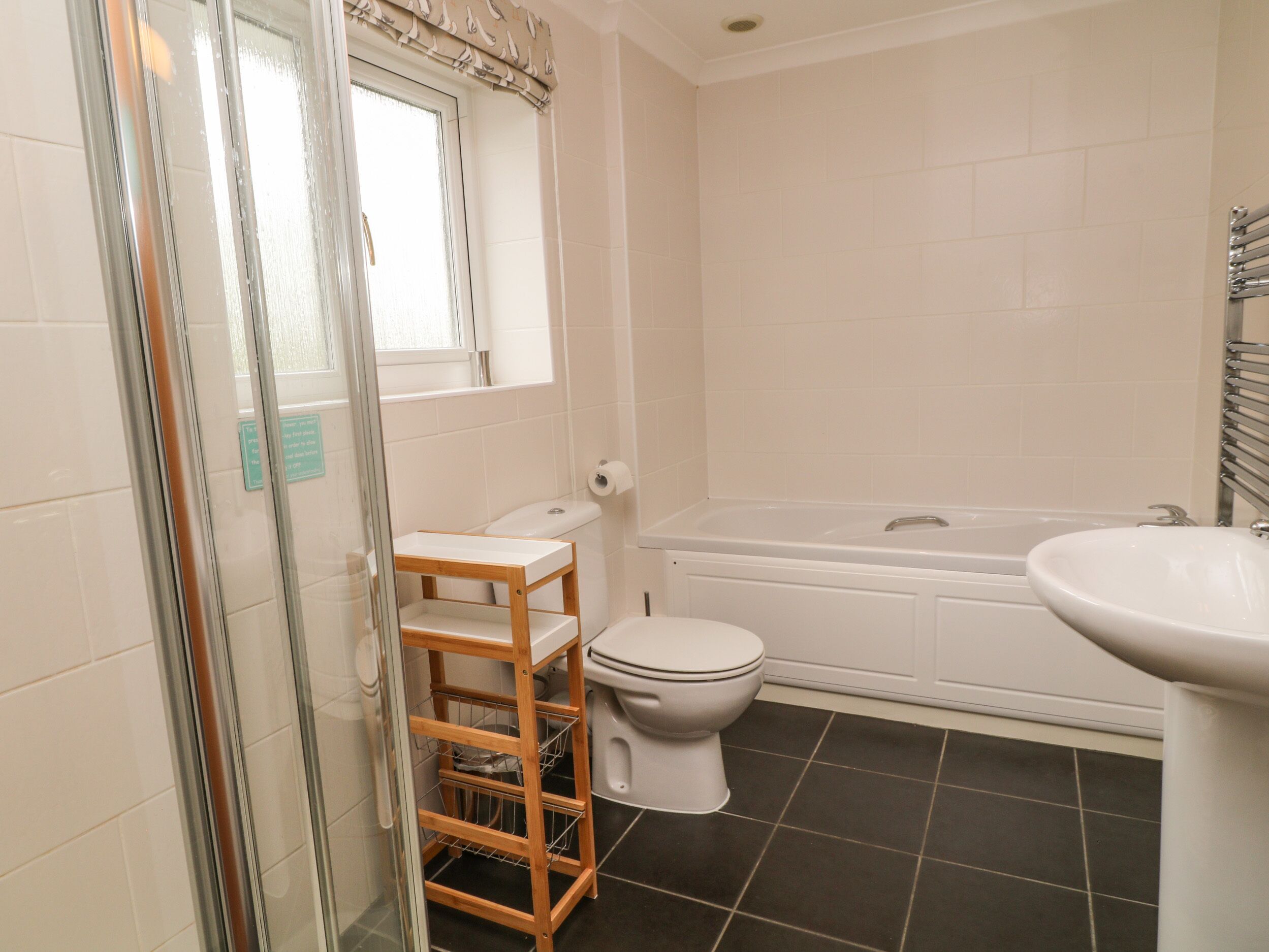 Un baño con cabina de ducha de vidrio, inodoro, bañera y lavamanos.