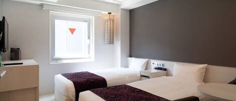 A modern hotel room with two beds, a desk, and a small table.