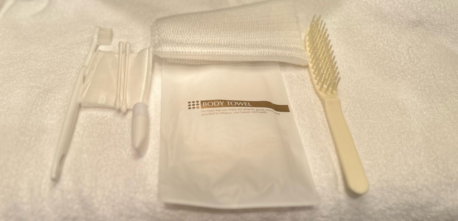 A body towel, a comb, and a pair of scissors on a white surface.