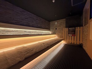 A sauna with wooden benches and a stone wall. - Hotel LiVEMAX Umeda Central  (Osaka)