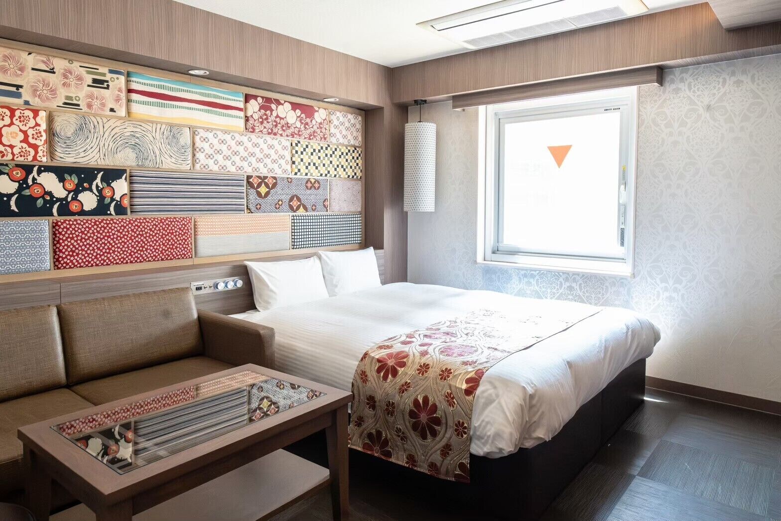 Una habitación de hotel moderna con una cama bien ordenada, un sofá y una mesita.