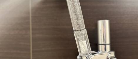A showerhead with water flowing from it, attached to a metallic pipe.