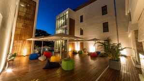 An outdoor patio area with wooden flooring, colorful bean bags, umbrellas, and potted plants. - Charming 2-Bed Apartment in Grand Baie (Grand Baie)