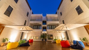A modern building with a courtyard, featuring colorful bean bags and umbrellas, and a central staircase. - Charming 2-Bed Apartment in Grand Baie (Grand Baie)