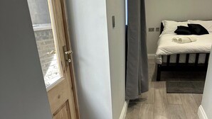 A bedroom with a bed, a window, and a door. - 1-Bed - Sleeps 2 - Acton Park & Stn Close (London)