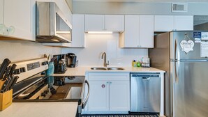 Une cuisine moderne avec des meubles blancs, des appareils en acier inoxydable et un lave-vaisselle.